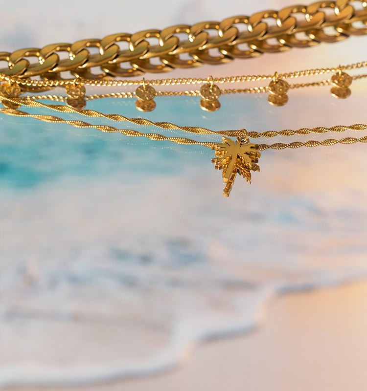 Goldene Ketten und Anhänger von PURELEI, inspiriert von tropischer Eleganz.