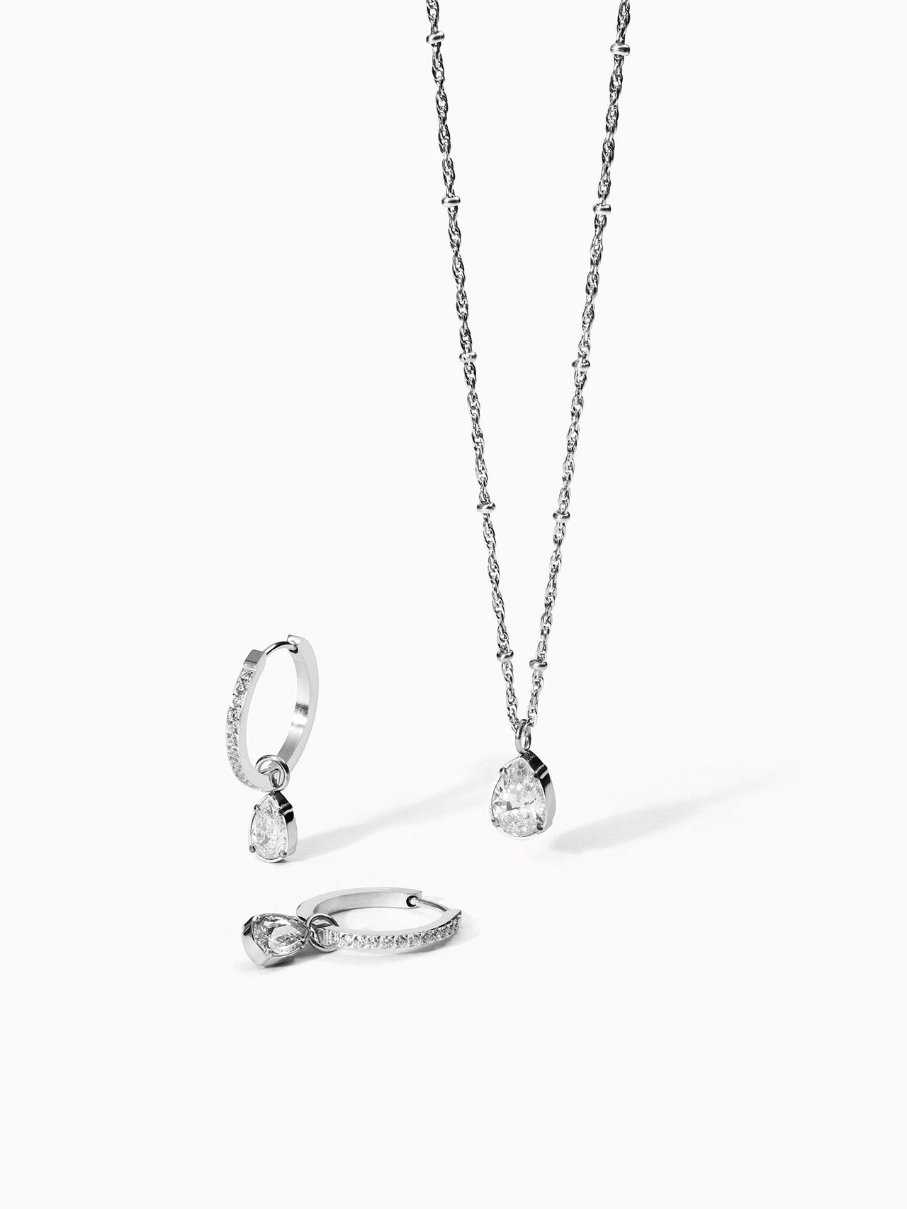 Silberne Kette und Creolen mit tropfenförmigen Anhängern von PURELEI, elegant und funkelnd.