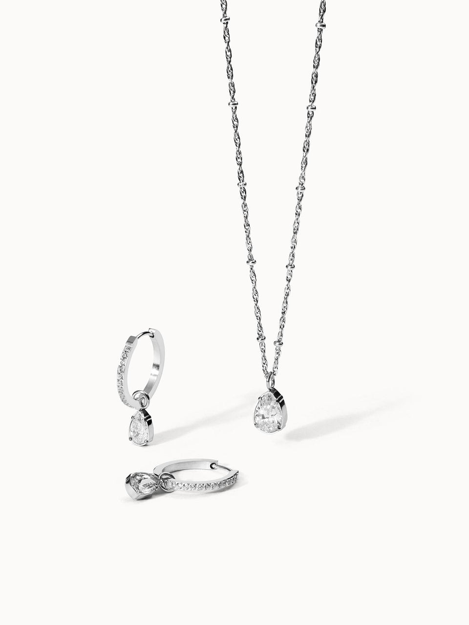 Silberne Kette und Creolen mit tropfenförmigen Anhängern von PURELEI, elegant und funkelnd.