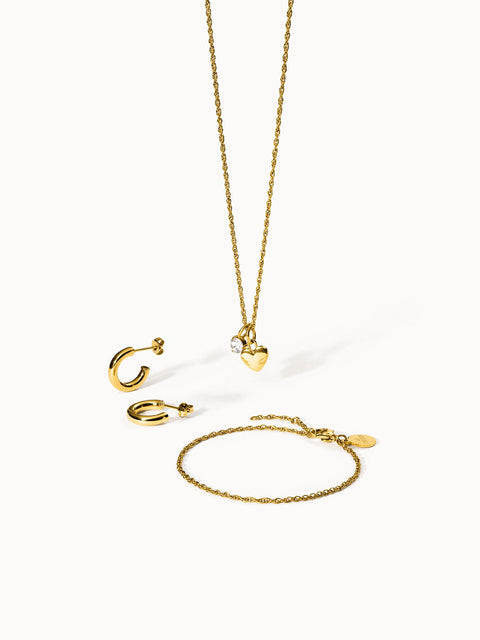 Goldene PURELEI Kette, Ohrringe und Armband mit Herzanhänger und funkelndem Stein.