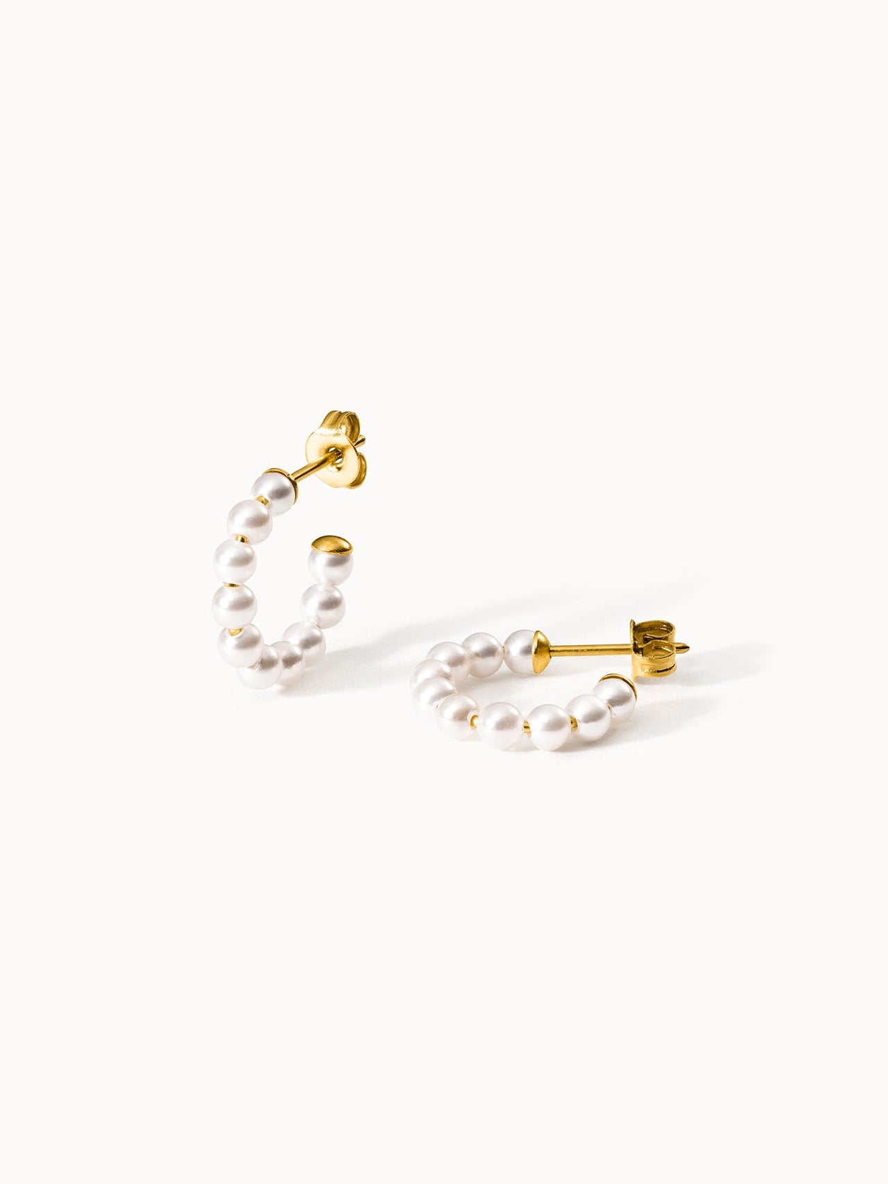 Goldene Creolen mit weißen Perlen von PURELEI, elegant und feminin.
