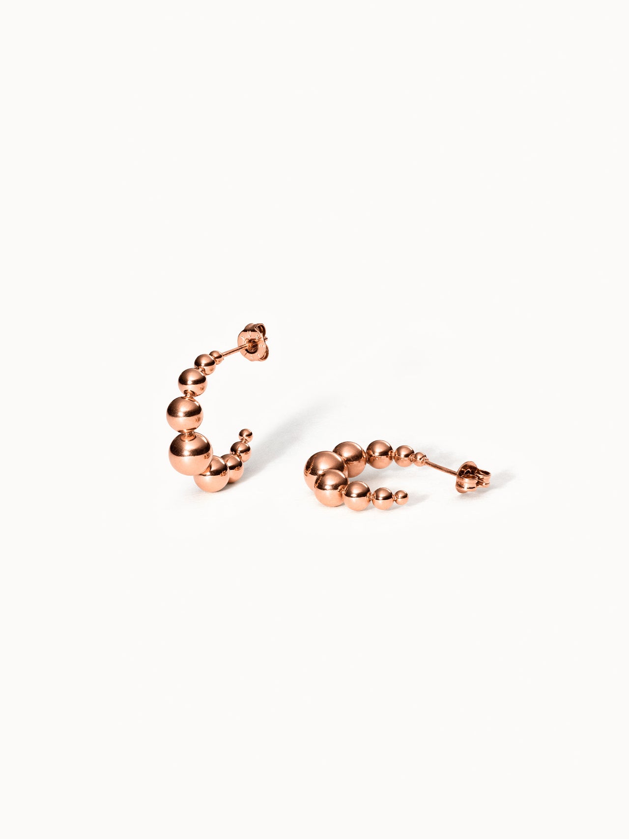 Roségoldene Creolen mit kugelförmigem Design von PURELEI, elegant und modern.