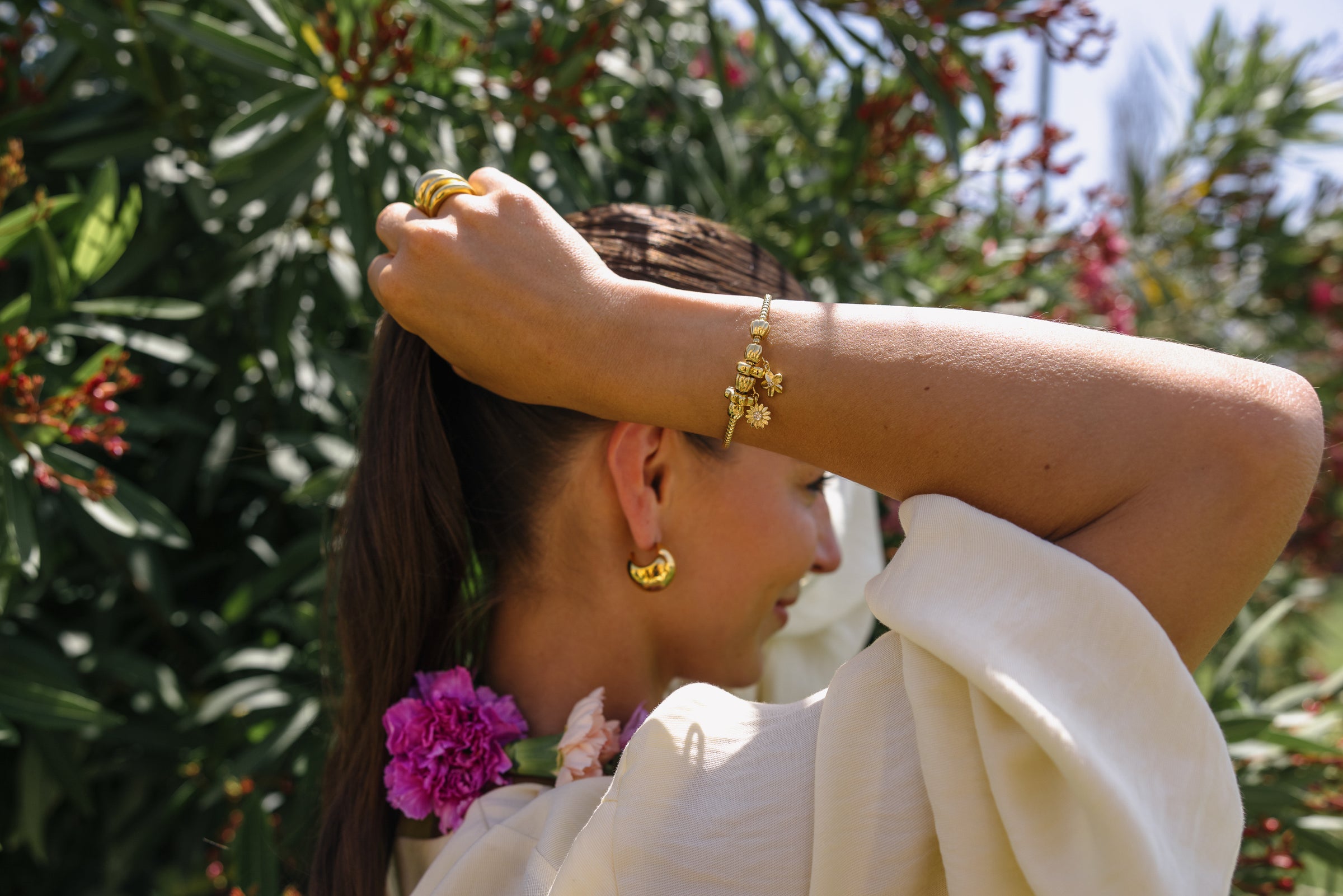 Roségoldenes Armband mit floralen Anhängern, getragen in tropischer Umgebung – PURELEI.