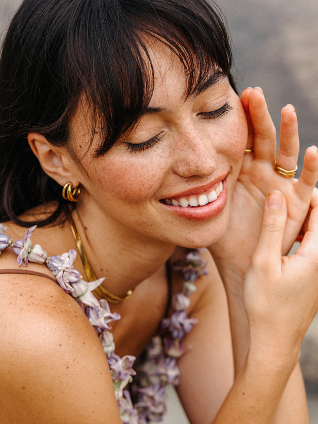 Feminine Schmuck von PURELEI, goldene Creolen und zarte Ringe, strahlende Aloha-Stimmung.