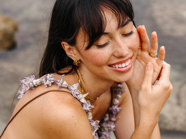 Zarte PURELEI Muschel-Halskette und goldene Ringe, strahlend und natürlich am Strand.