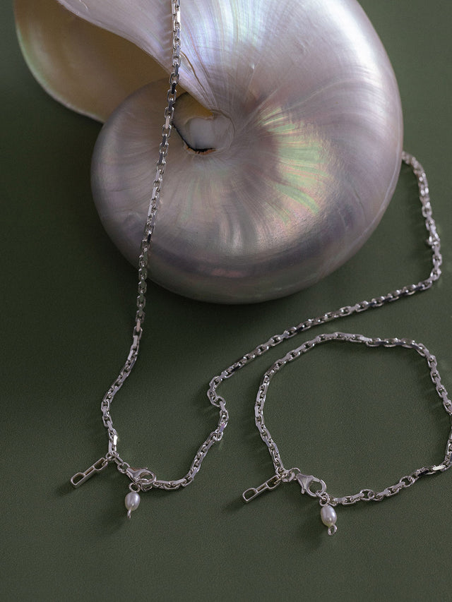 Silberne Kette und Armband mit Perlenanhänger, elegant auf grünem Hintergrund, PURELEI.