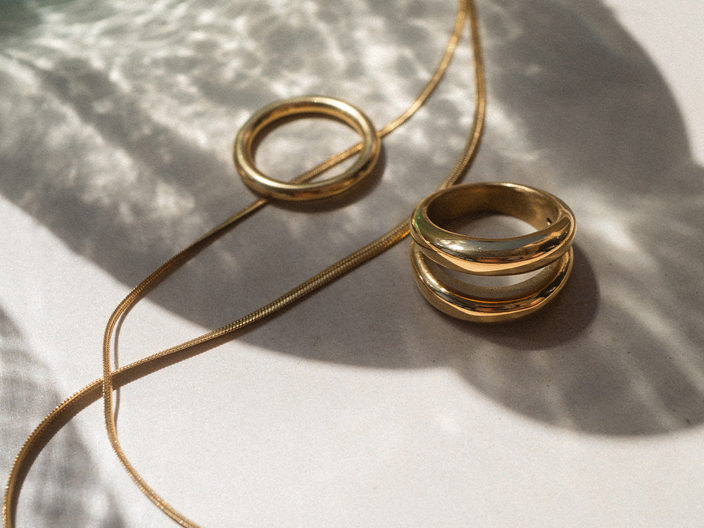 Goldene Ringe und Kette von PURELEI auf hellem Hintergrund, elegant und modern.