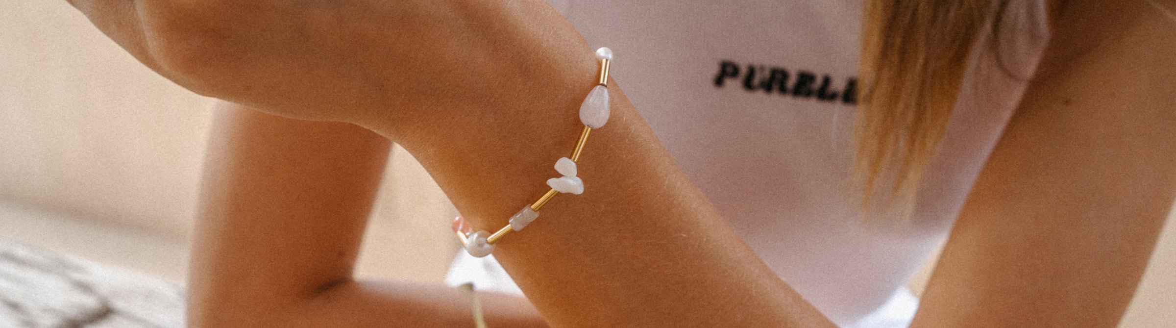 Zartes Armband aus weißen Steinen, getragen am Handgelenk, inspiriert von PURELEI.