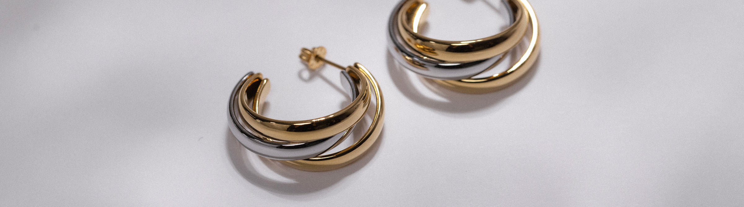 Goldene Creolen mit geschwungenem Design von PURELEI, elegant und modern.