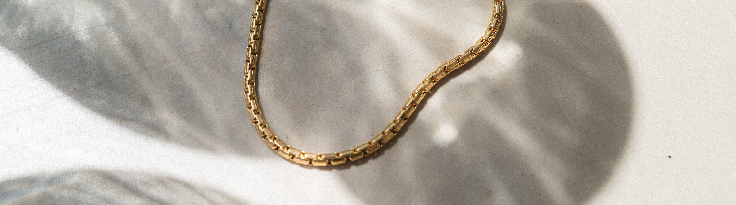 Silberne Kette mit elegantem Design auf sanftem Hintergrund, PURELEI inspiriert.