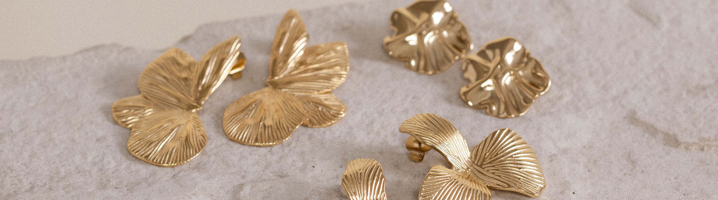 Goldene Ohrringe mit Blattdesign auf hellem Untergrund von PURELEI.