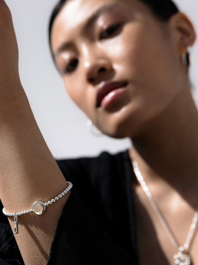 Silbernes Armband mit runden Perlen und Anhänger, getragen von einer Frau, PURELEI.