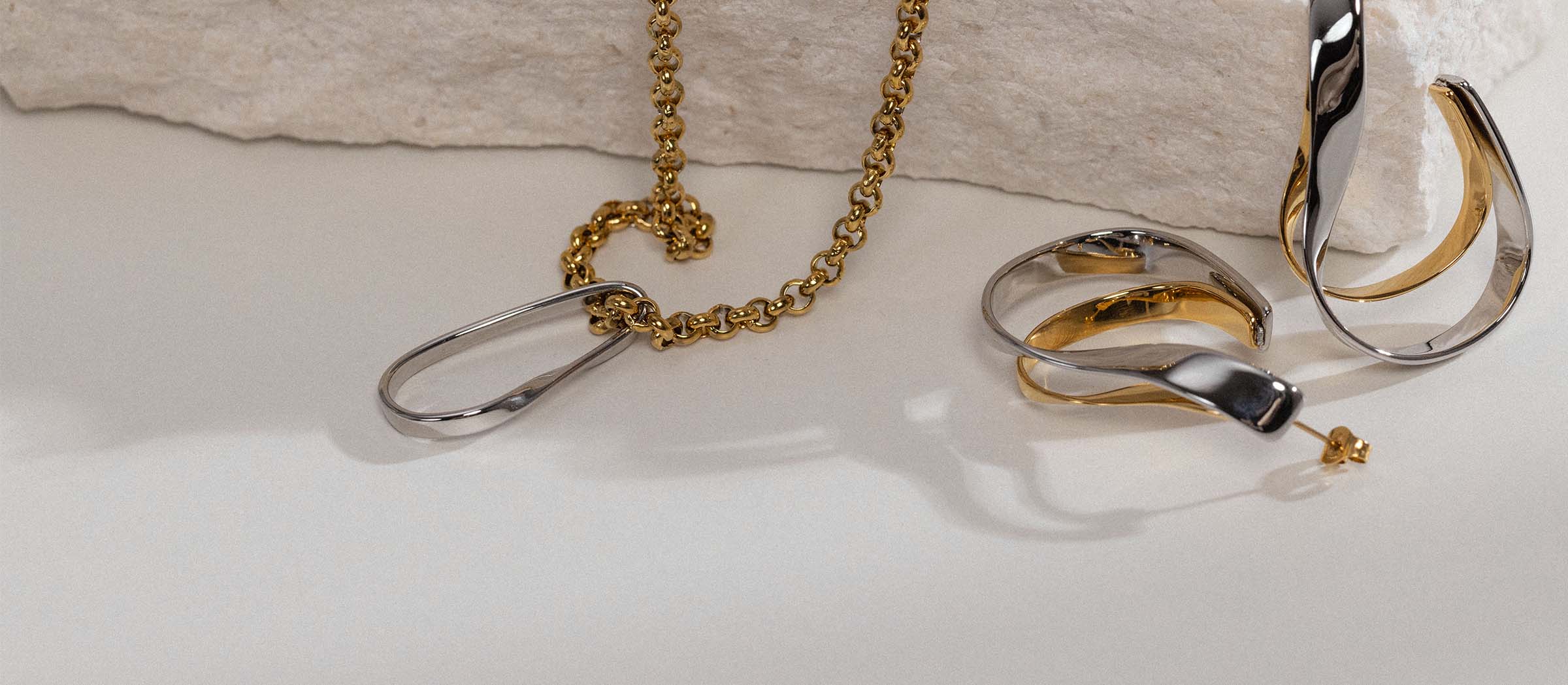 Goldene Kette und Ohrringe von PURELEI auf hellem Hintergrund, elegant und modern.