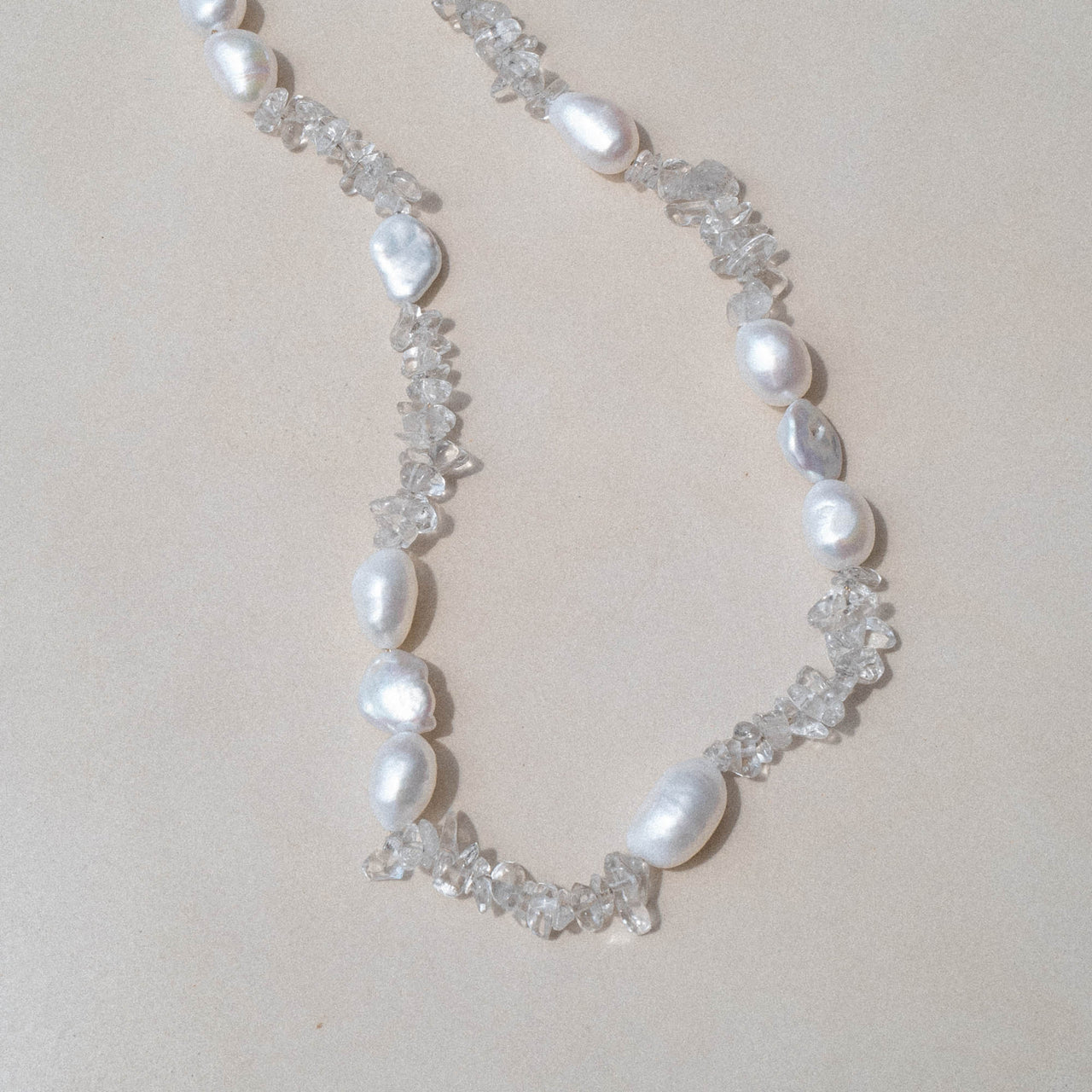PURELEI Crystal Wave Kette mit schimmernden Keshi-Perlen und Bergkristallen auf hellem, minimalistischem Hintergrund