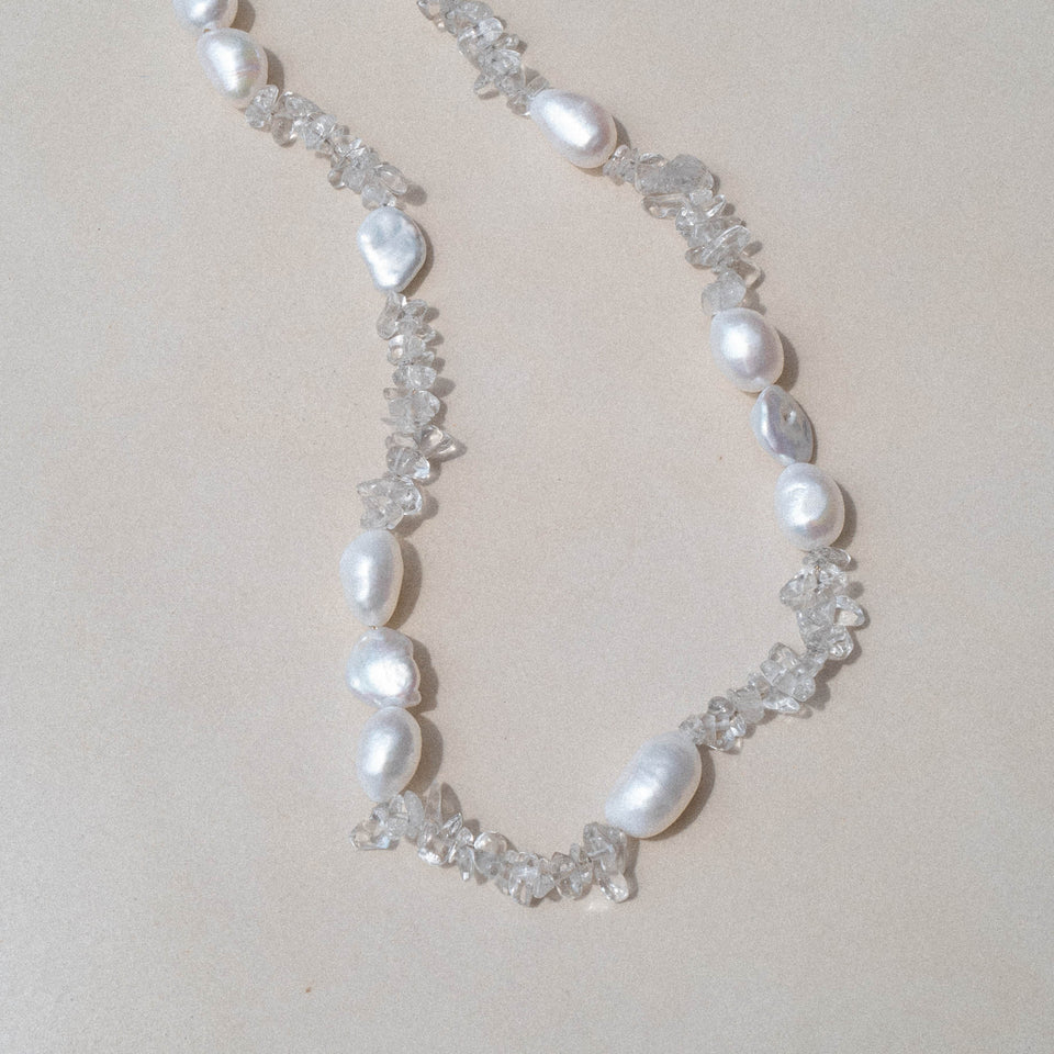 PURELEI Crystal Wave Kette mit schimmernden Keshi-Perlen und Bergkristallen auf hellem, minimalistischem Hintergrund