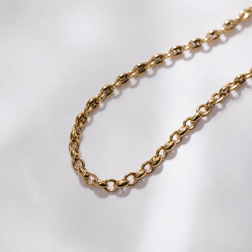 Goldene Kette mit ovalen Gliedern auf hellem Hintergrund, PURELEI inspiriert.