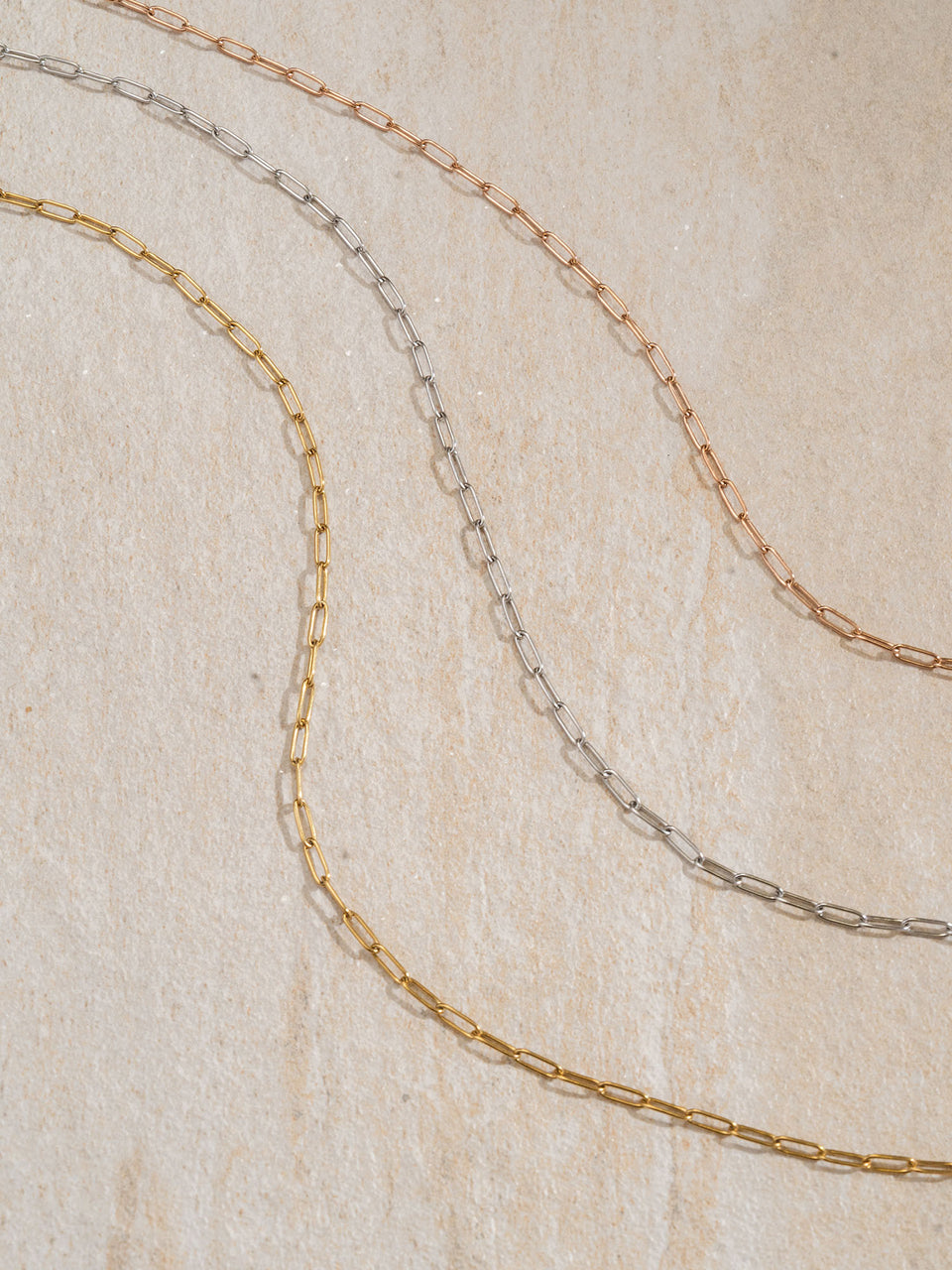 Flex Charm Kette in Gold, Silber und Roségold, filigrane Gliederkette auf hellem Naturstein – PURELEI Eleganz.