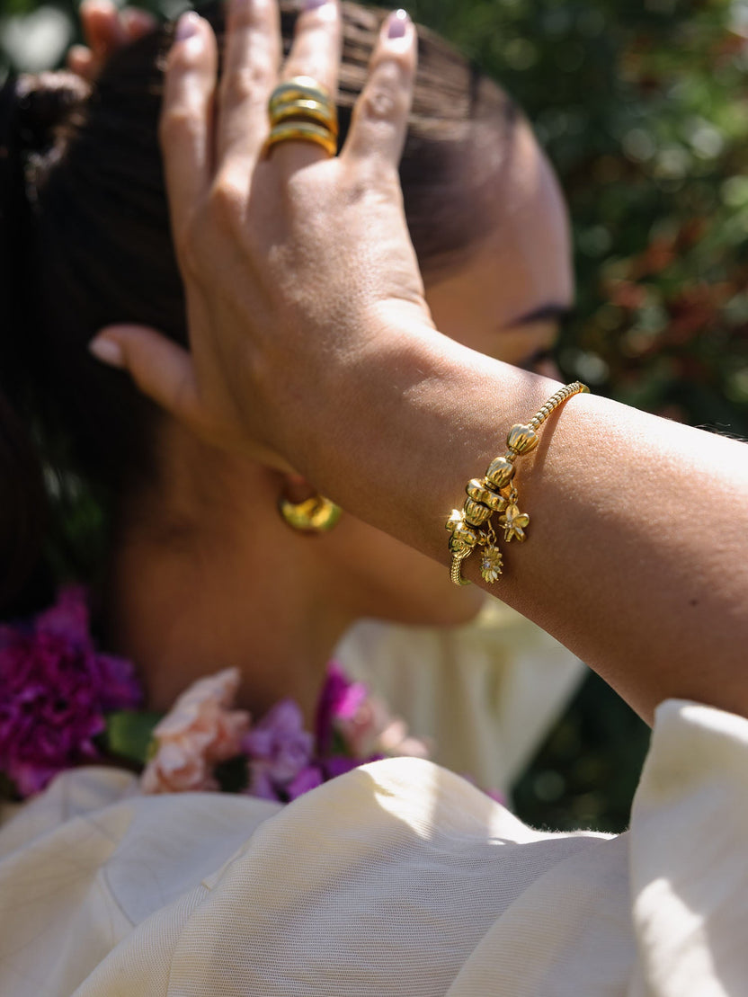 PURELEI Lei Plumeria Charm in 14K Gold vergoldet, zart und elegant an Handgelenk im Sonnenlicht getragen