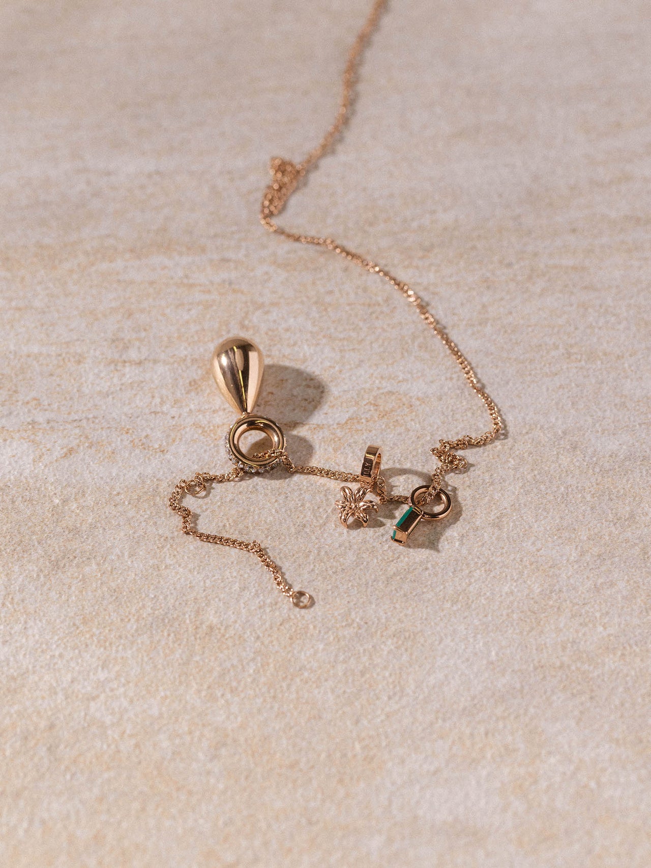 Kaula Kette in 18K Roségold mit feinem, gedrehtem Design und zarten Anhängern auf hellem Stein – PURELEI.
