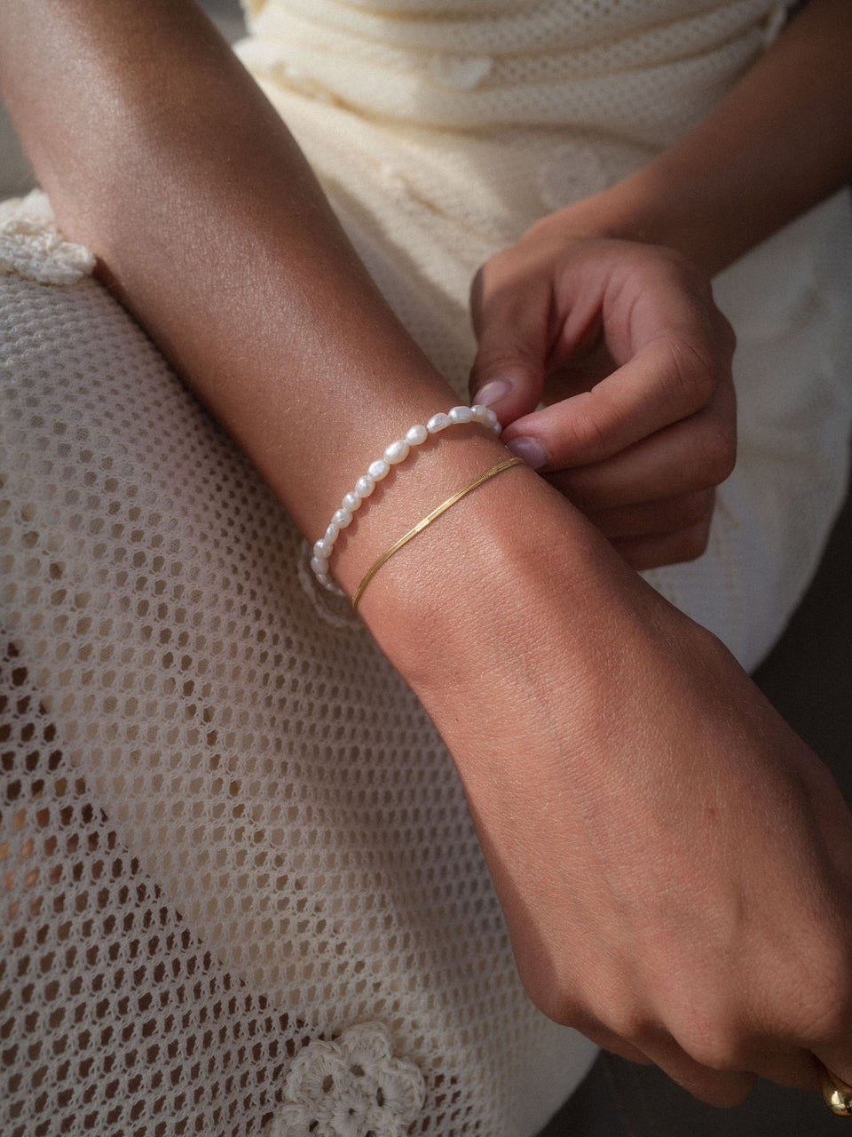 Zartes PURELEI Armband aus Perlen und feinem Gold, getragen auf einem Handgelenk.