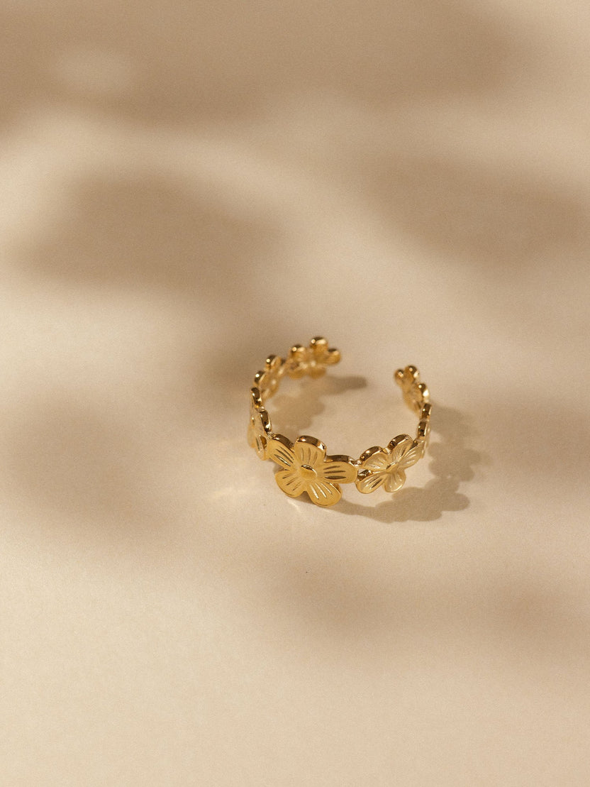 Goldenes Blumenarmband von PURELEI, filigran und elegant, auf sanftem Hintergrund.