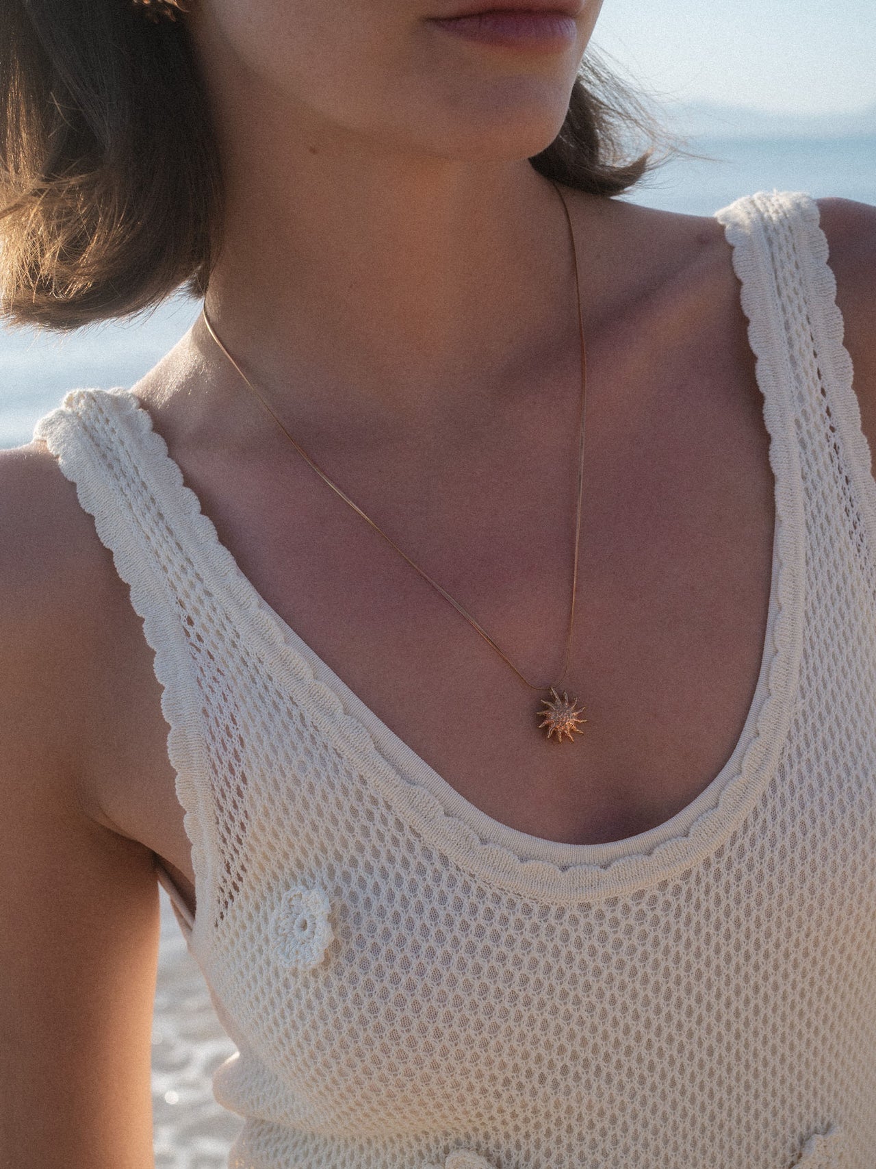 PURELEI Iconic Sun Kette in Roségold mit filigraner Snake-Chain und sonnigem Anhänger am Strand getragen.