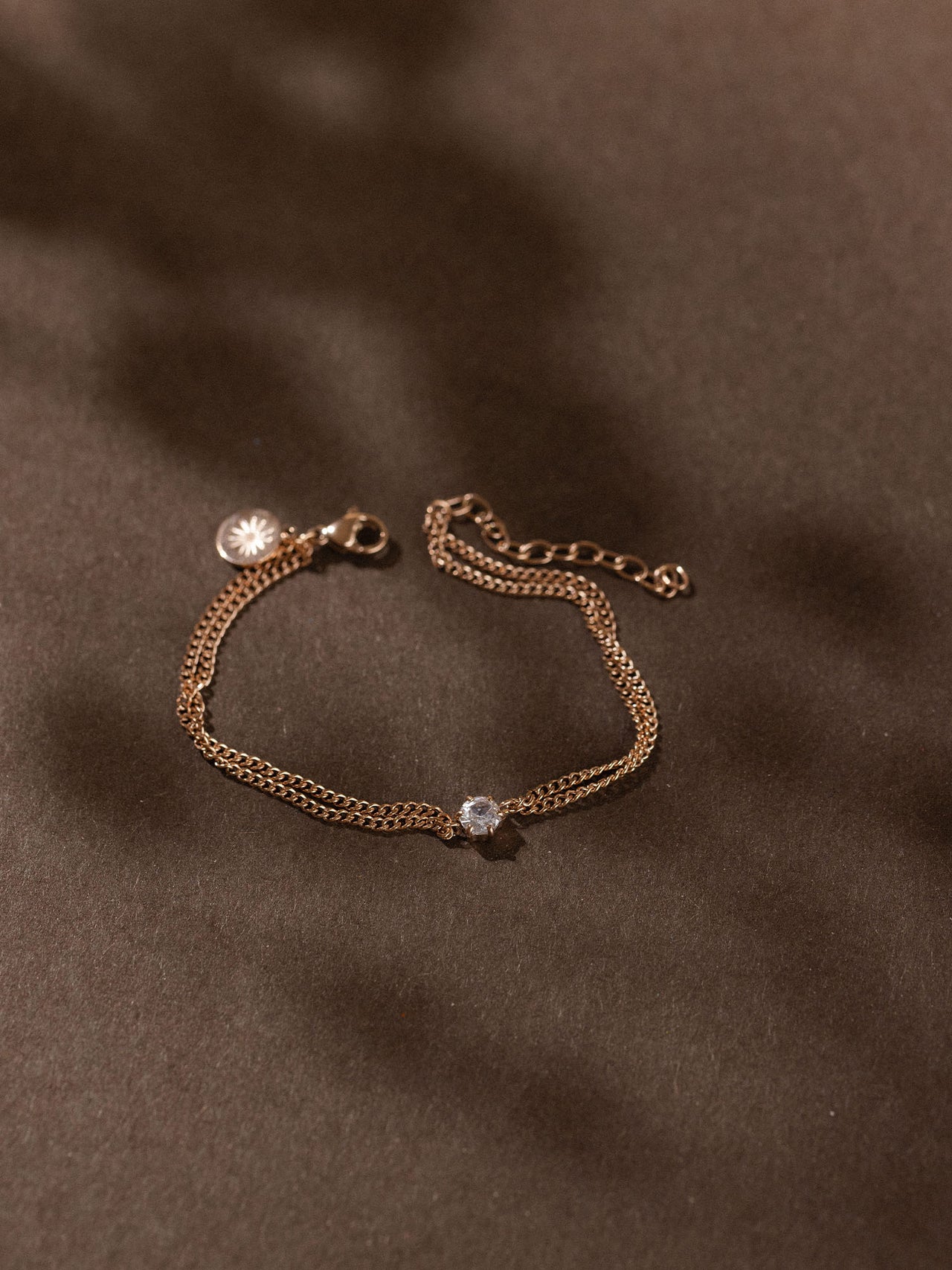 Zartes, roségoldenes Armband mit facettiertem Anhänger von PURELEI auf dunklem Hintergrund.