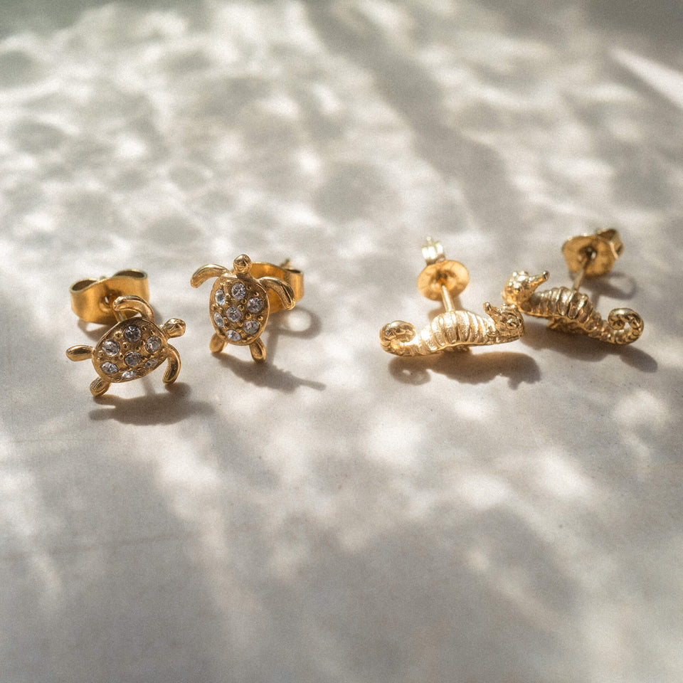 Goldene Ohrringe in Schildkröten- und Muschel-Design von PURELEI, funkelnd und verspielt.