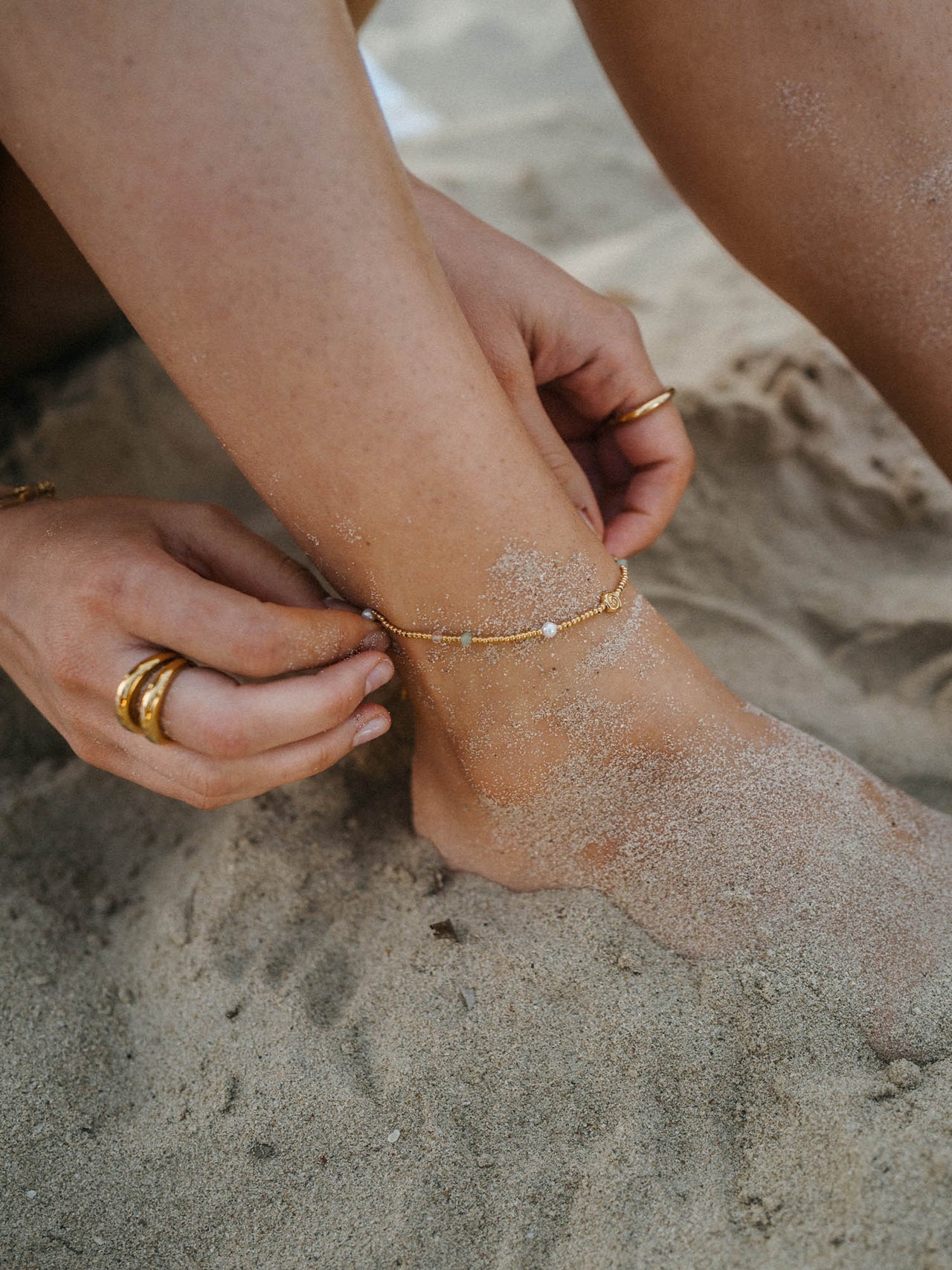 Zartes, silbernes Fußarmband mit Muschel-Anhänger, getragen im Sand – PURELEI.