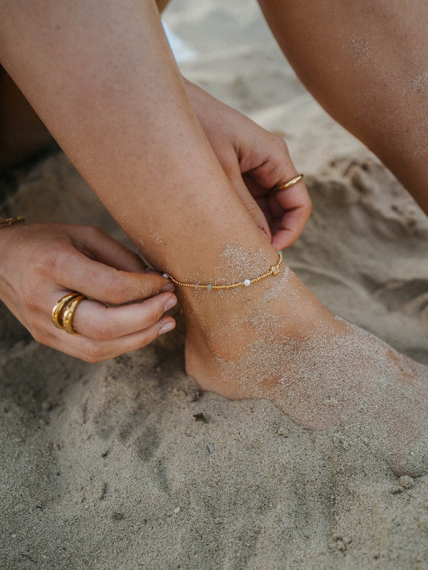 Zartes, silbernes Fußarmband mit Muschel-Anhänger, getragen im Sand – PURELEI.
