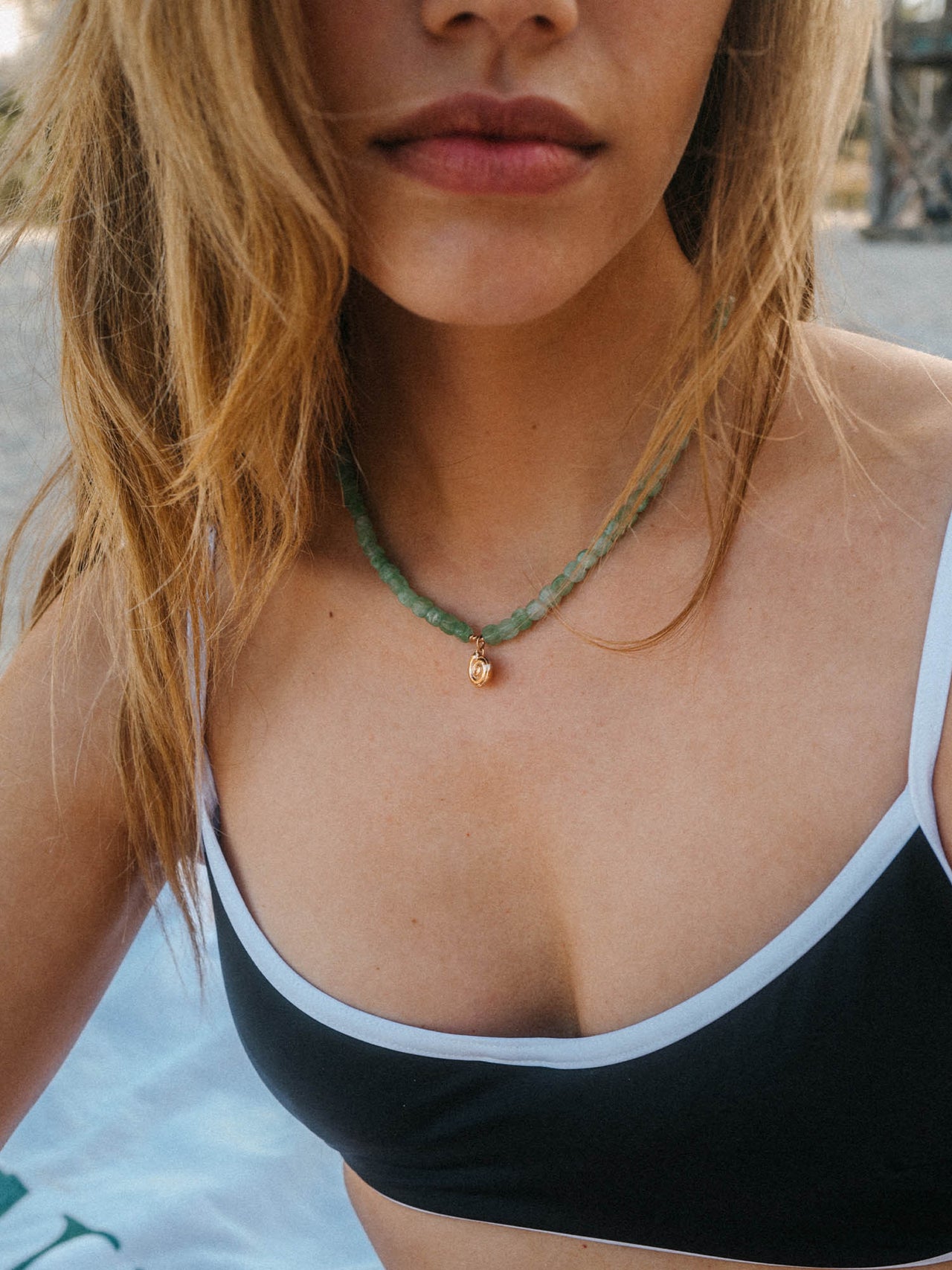 Zarte PURELEI Kette mit Muschel-Anhänger, getragen am Strand, in sanften Erdtönen.