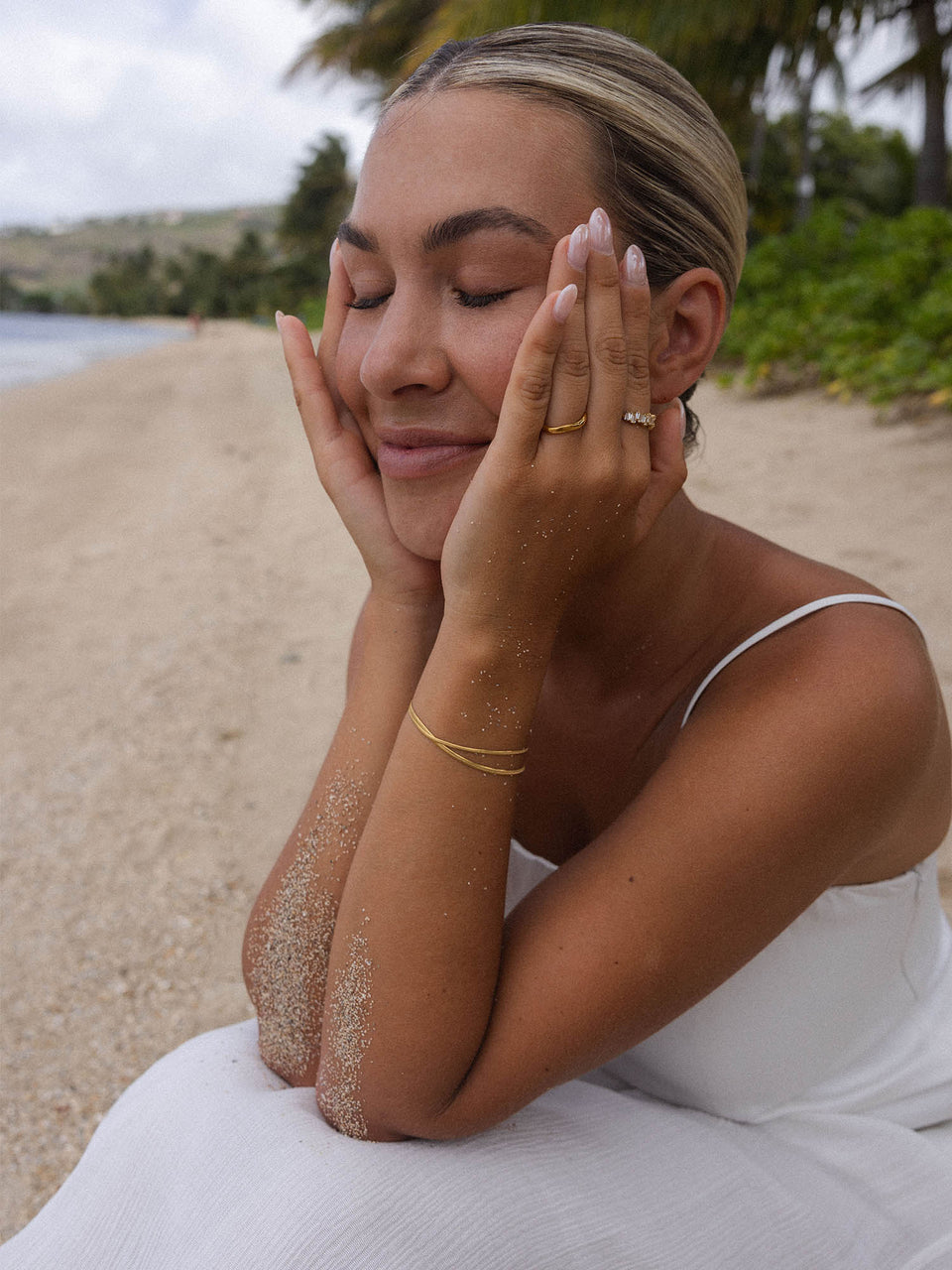 Feminines PURELEI Armband aus Roségold, getragen am Strand, umgeben von sandiger Atmosphäre.
