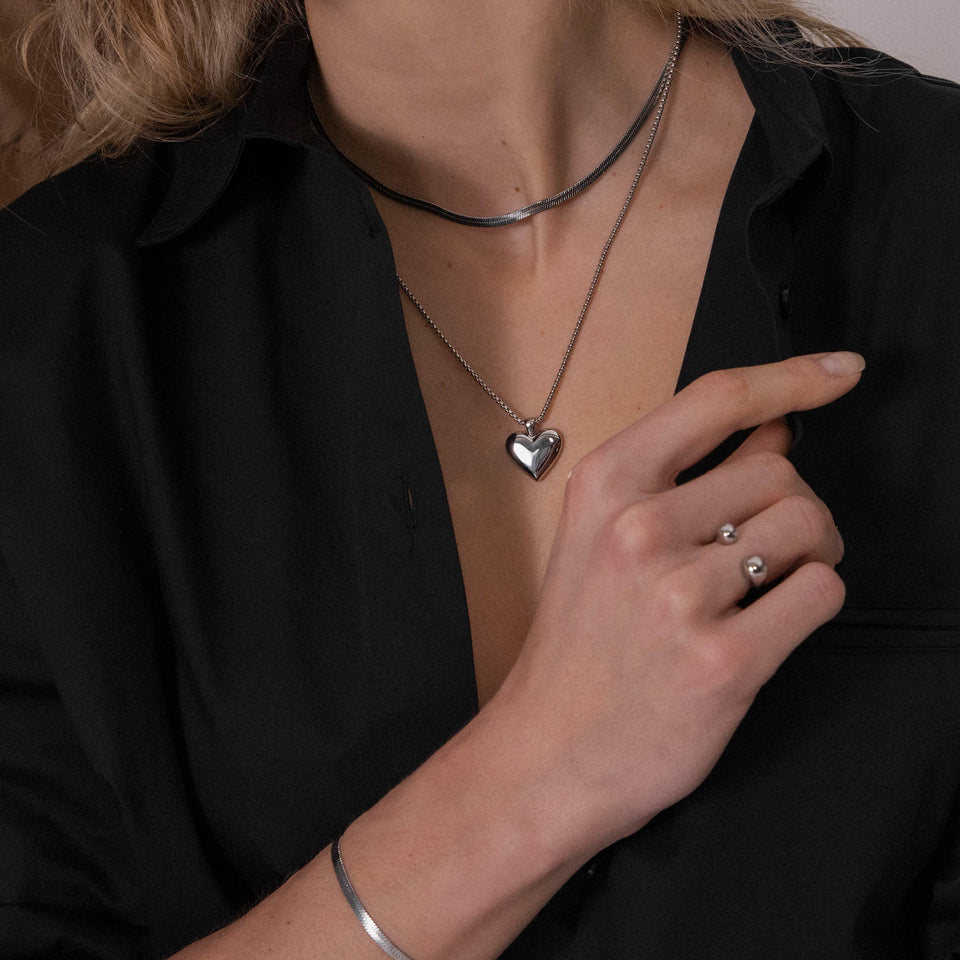 Goldene Herz-Halskette von PURELEI, getragen mit eleganter Bluse, warmes Licht.