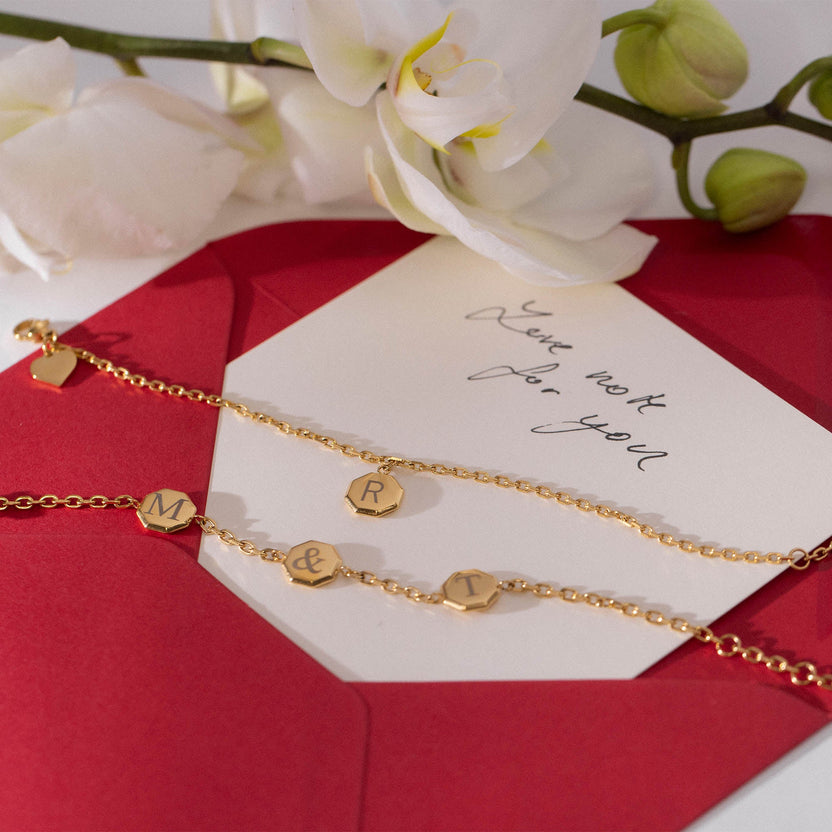 Goldene personalisierte Armbänder auf rotem Umschlag, PURELEI inspiriert.