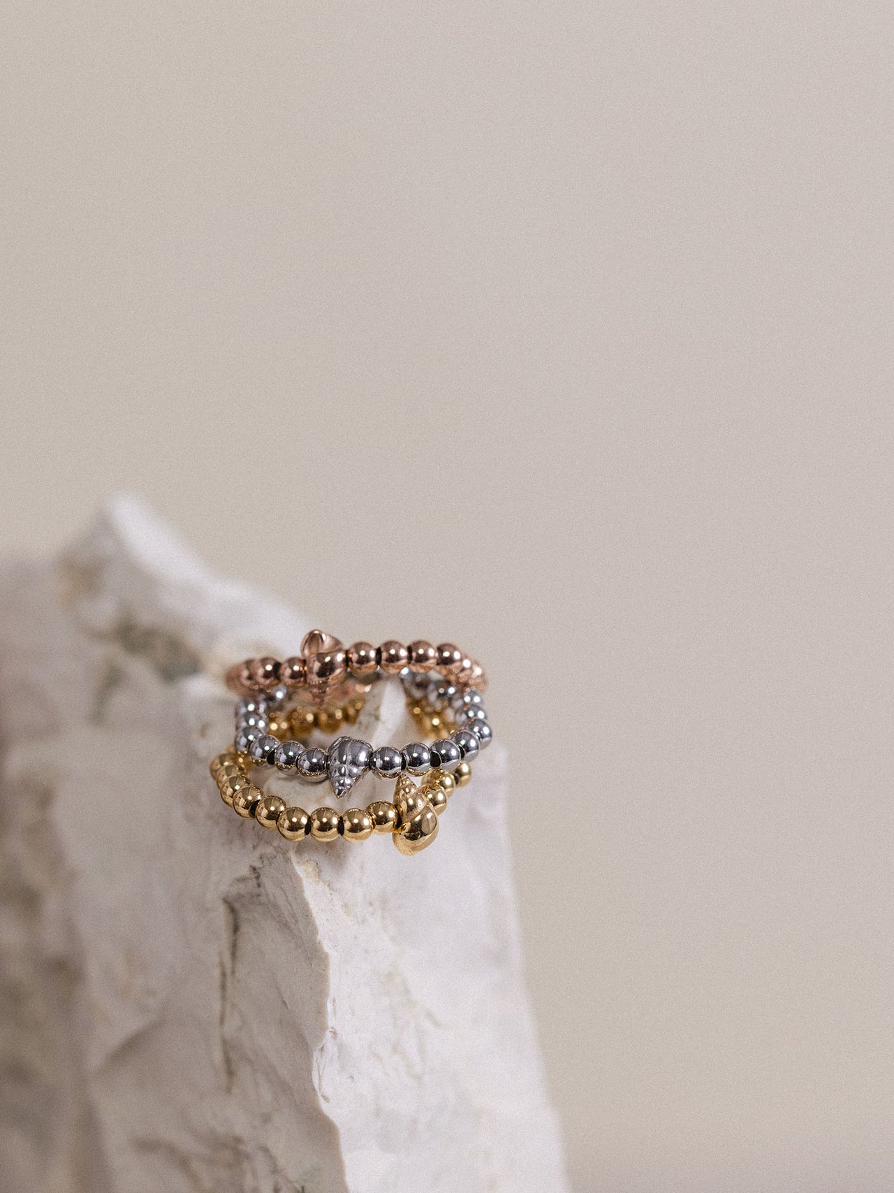 Oceanside Ring von PURELEI in Gold, Silber und Roségold mit Muschel-Detail, elegant auf hellem Stein arrangiert.
