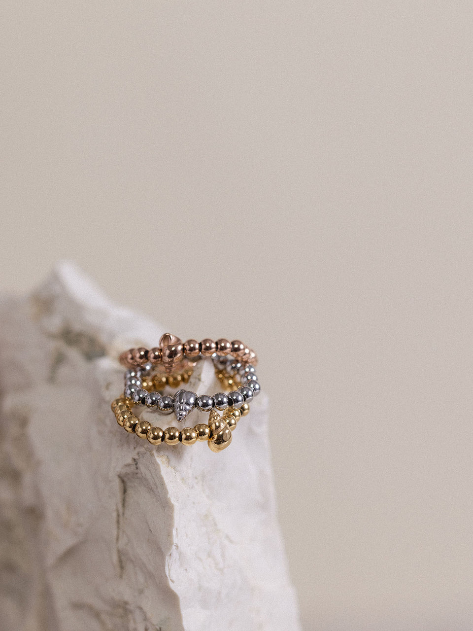 Oceanside Ring von PURELEI in Gold, Silber und Roségold mit Muschel-Detail, elegant auf hellem Stein arrangiert.