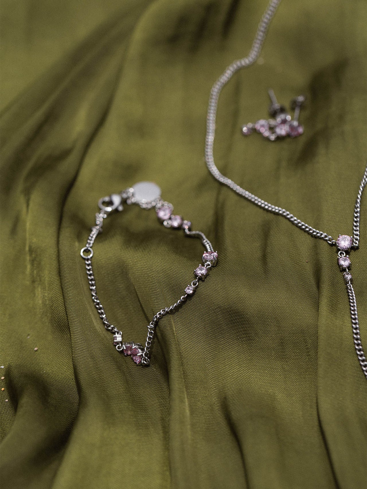 Silberne Kette und Armband auf grünem Stoff, PURELEI inspiriert von Eleganz und Feminität.