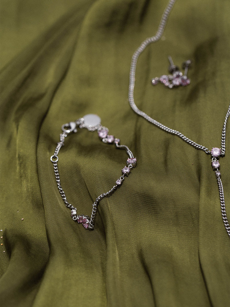 Silberne Kette und Armband auf grünem Stoff, PURELEI inspiriert von Eleganz und Feminität.