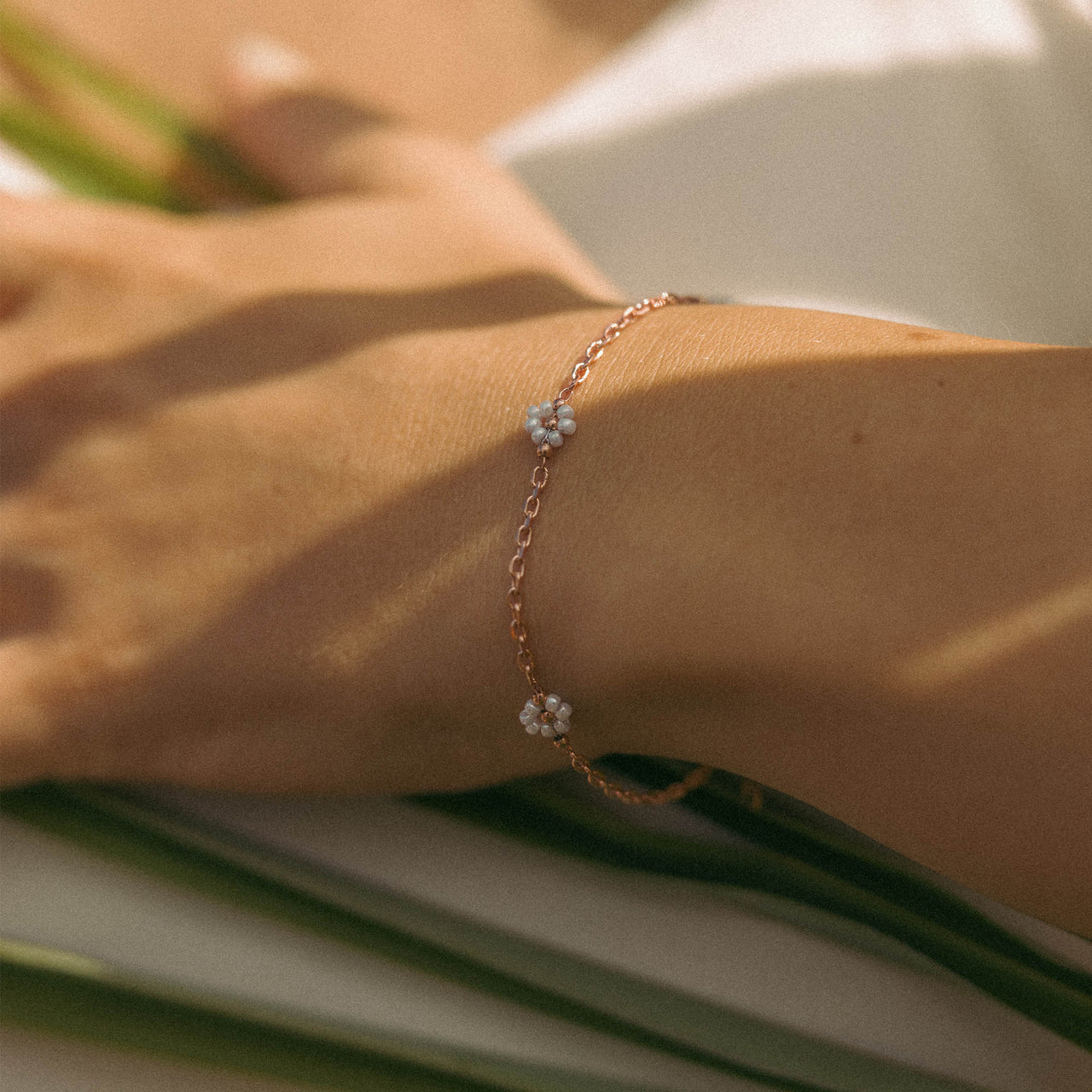 Zartes, roségoldenes Armband mit blütenförmigen Details von PURELEI, getragen am Handgelenk.