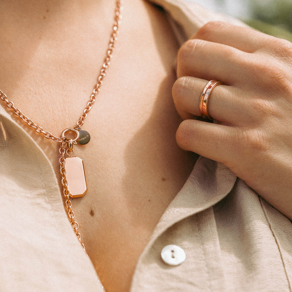 Roségoldene Kette mit Anhängern, getragen auf einem hellen Hemd – PURELEI Eleganz.