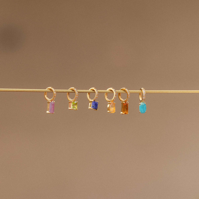 Goldene Anhänger mit bunten Steinen auf feinem Draht von PURELEI, elegant und modern.