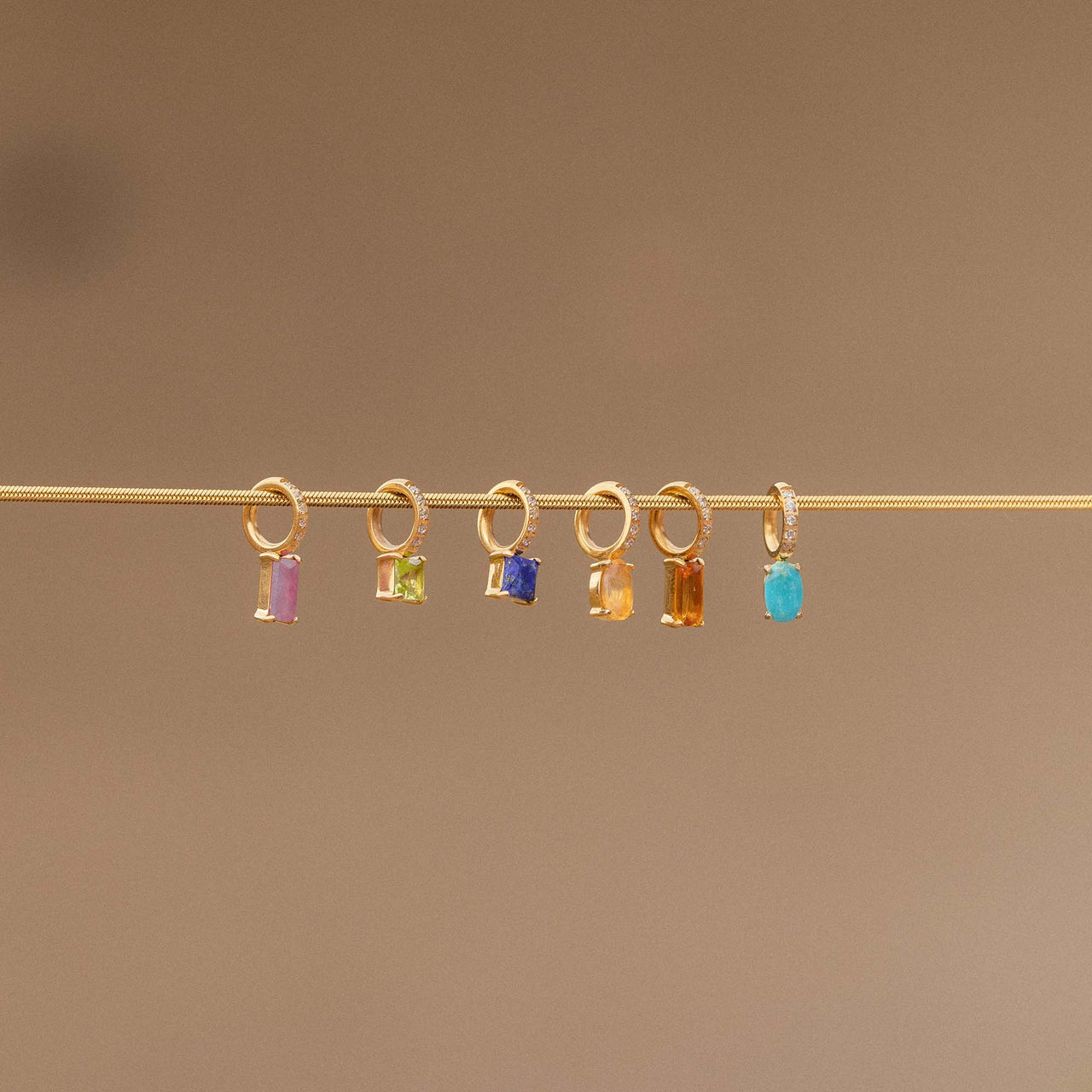 Goldene Anhänger mit bunten Steinen auf feinem Draht, PURELEI inspiriert.