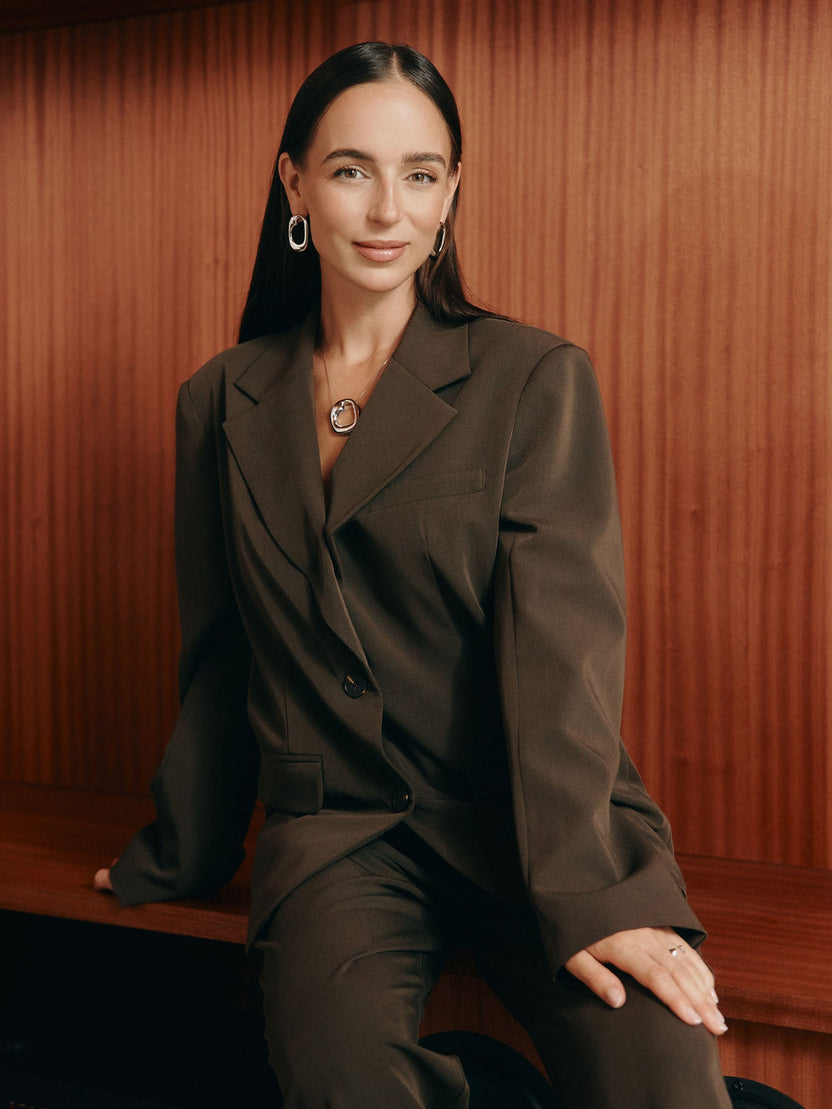 Elegante PURELEI Kette mit Anhänger, getragen in einem stilvollen, braunen Anzug.