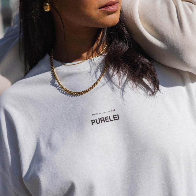 Goldene Kette über weißem Sweatshirt mit PURELEI-Logo, lässig und modern.