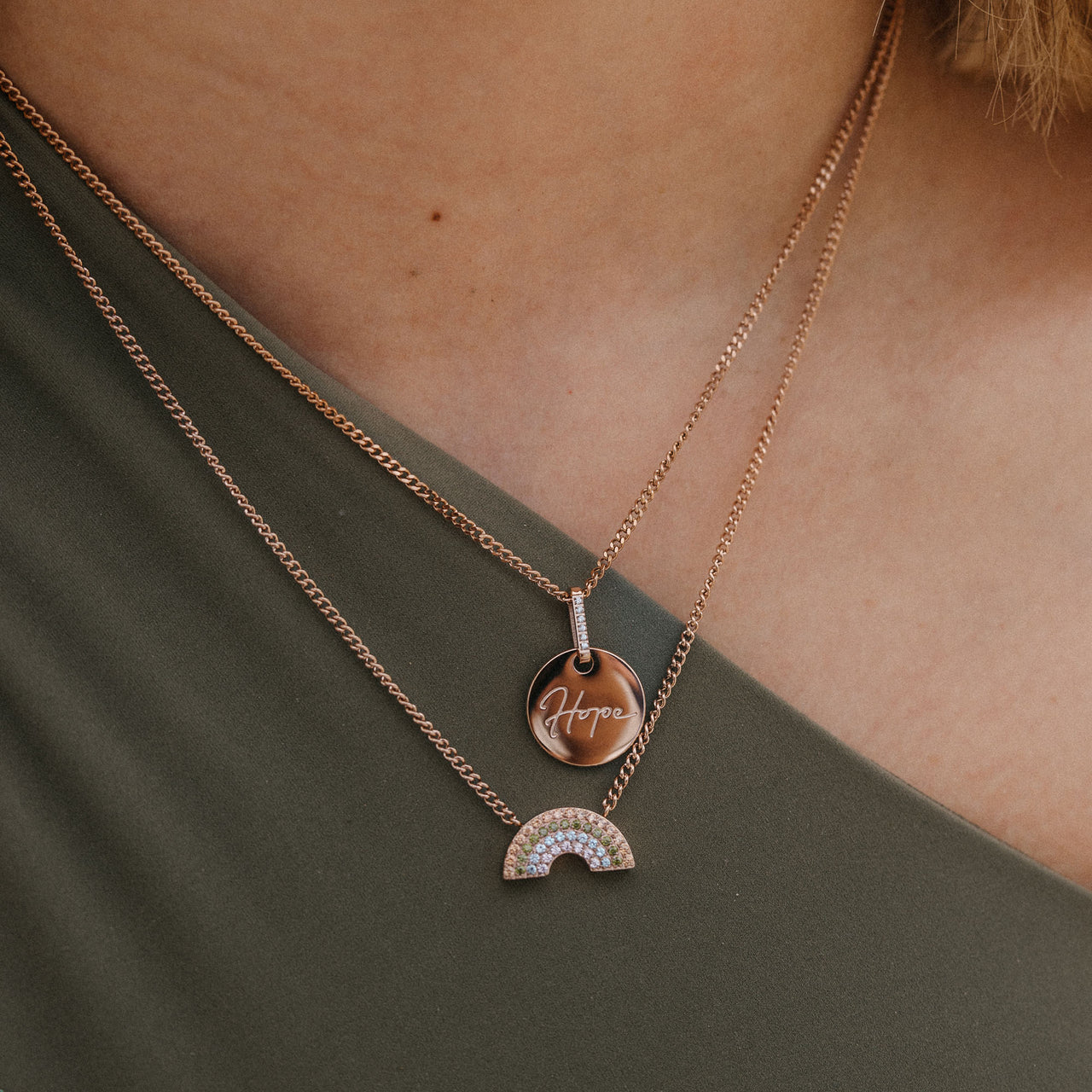 Zwei roségoldene Ketten mit Anhängern Hope und Regenbogen von PURELEI, elegant und inspirierend.