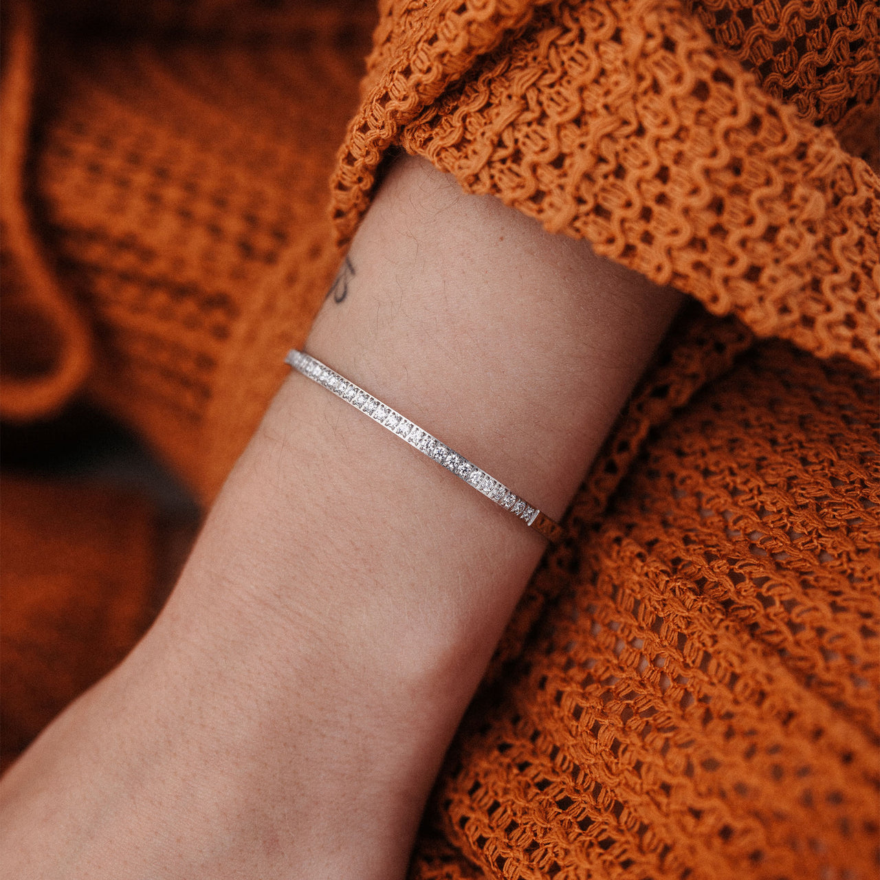 Zartes, roségoldenes Armband am Handgelenk, umgeben von warmen Erdtönen – PURELEI.