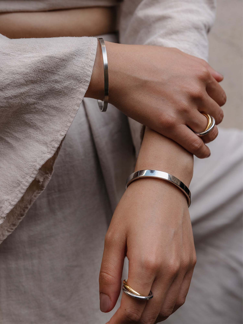Silberne Armbänder und Ringe von PURELEI, elegant und modern, getragen auf zarten Händen.