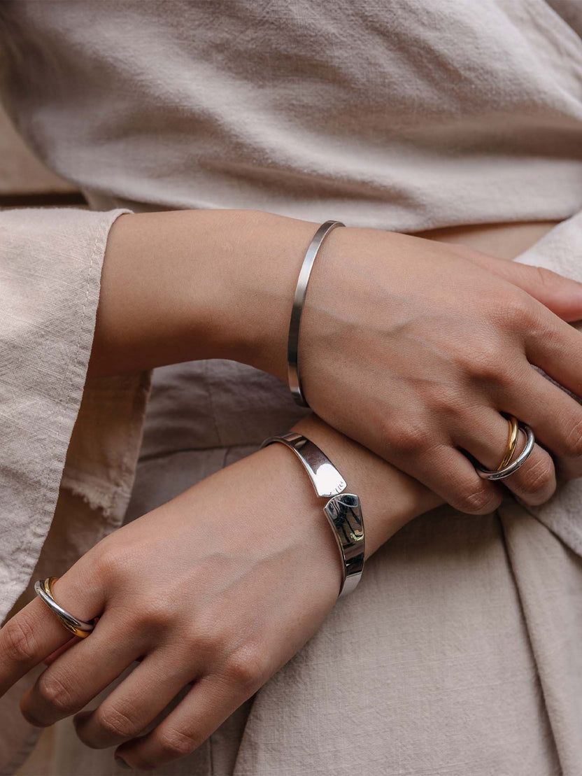 Silberne Armbänder und Ringe von PURELEI, elegant und modern, getragen auf zarten Händen.