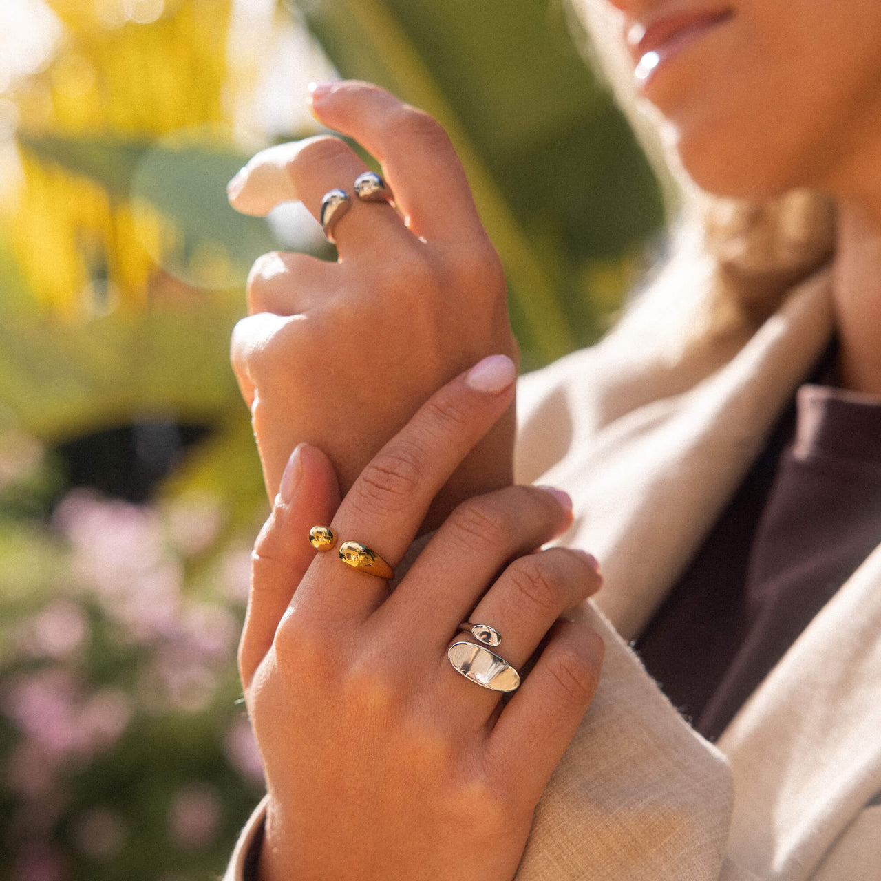 Zwei Ringe aus Gold und Silber, elegant getragen, umgeben von tropischer Atmosphäre - PURELEI.
