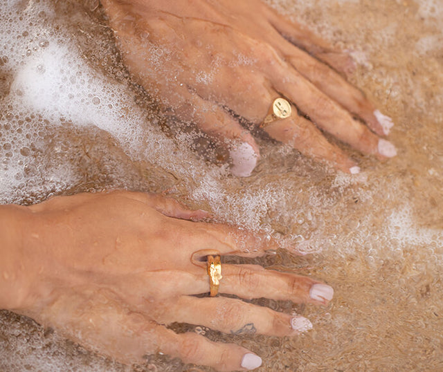 Goldene Ringe von PURELEI in Wasser, elegant und feminin, umgeben von sanften Wellen.